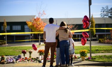 Community members grieve at the site of a makeshift memorial in front of Silver Rail Elementary School in Bend