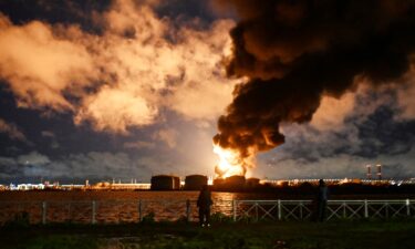 People watch the burning oil terminal following an air attack in Saint Petersburg