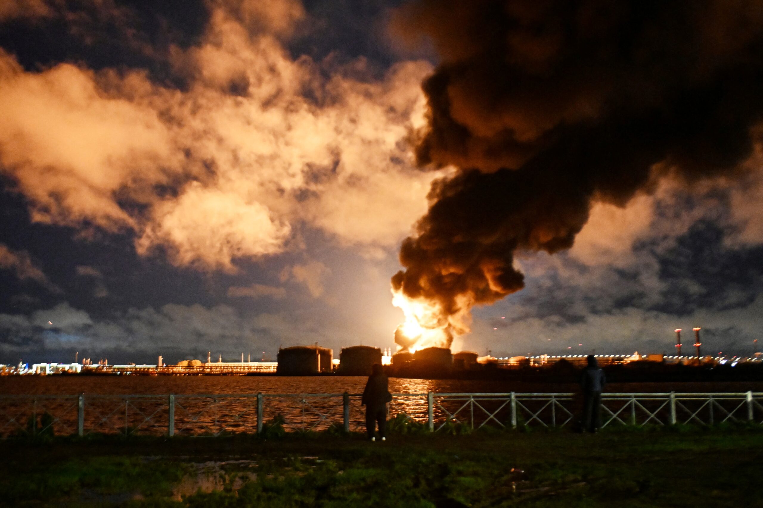 <i>AFP/Getty Images via CNN Newsource</i><br/>People watch the burning oil terminal following an air attack in Saint Petersburg