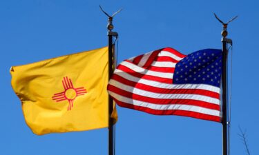 The New Mexico state flag and the American flag fly side-by-side in Santa Fe