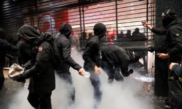 Masked protesters force a metal grid to the Galeries Lafayette to loot items in Paris on Oct. 17
