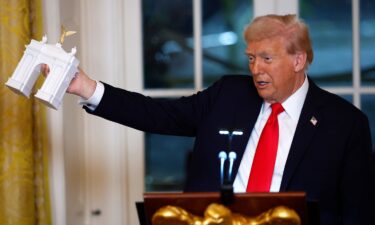 President Donald Trump holds a model of his proposed triumphal arch as he delivers remarks during a ballroom fundraising dinner in the East Room of the White House on October 15